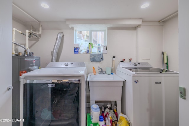 clothes washing area with water heater, sink, and washer and dryer