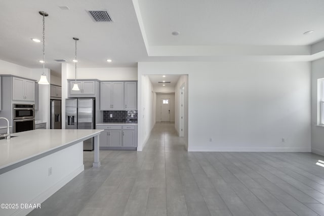1316 Loftwedge Cir, Daytona Beach, FL 32124 - kitchen with appliances with stainless steel finishes, gray cabinets, backsplash, light countertops, and pendant lighting