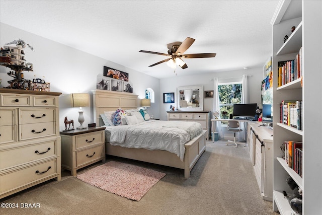 bedroom featuring built in desk, a textured ceiling, light colored carpet, and ceiling fan