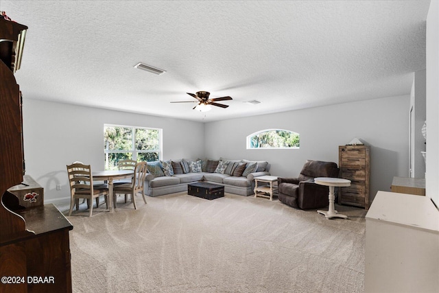 carpeted living room featuring ceiling fan and a textured ceiling