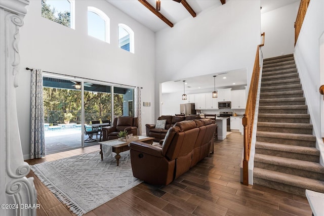 living room with beamed ceiling, a towering ceiling, dark hardwood / wood-style floors, and plenty of natural light