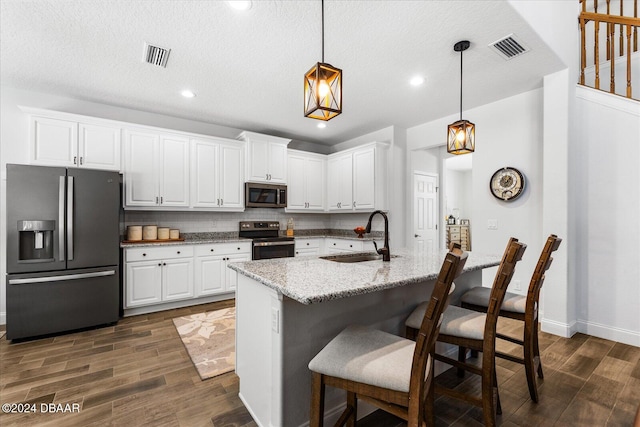 kitchen featuring appliances with stainless steel finishes, dark hardwood / wood-style floors, hanging light fixtures, sink, and white cabinets