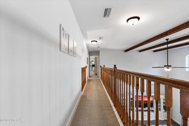 hall with beamed ceiling, a textured ceiling, and carpet