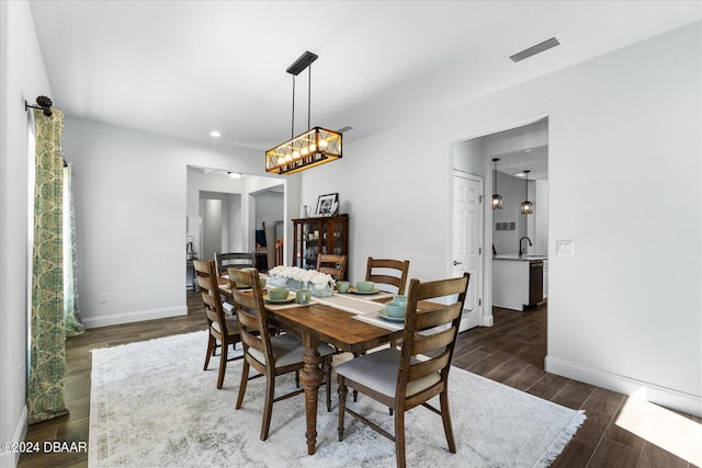 dining area featuring dark wood-type flooring and a notable chandelier