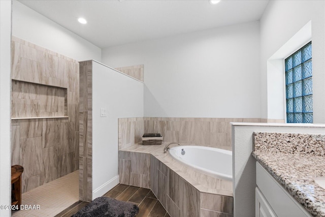 bathroom with wood-type flooring, independent shower and bath, and vanity