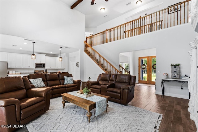 living room featuring french doors, a towering ceiling, hardwood / wood-style flooring, beamed ceiling, and ceiling fan