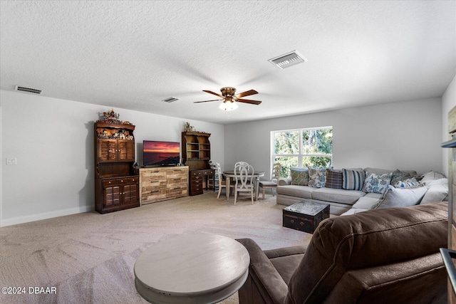 carpeted living room with ceiling fan and a textured ceiling