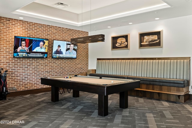 recreation room with a tray ceiling, billiards, brick wall, and dark colored carpet