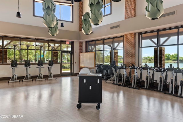 interior space with a water view, a towering ceiling, and a healthy amount of sunlight