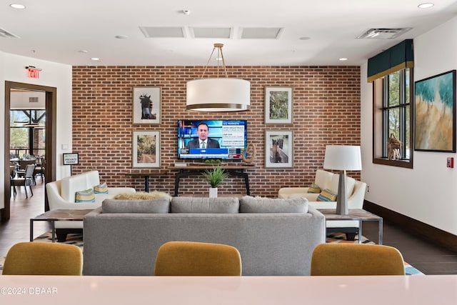 living room with hardwood / wood-style floors and brick wall