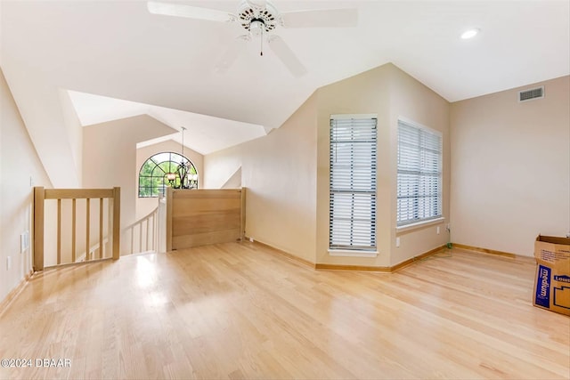 additional living space featuring wood-type flooring, ceiling fan with notable chandelier, and lofted ceiling