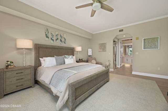 bedroom featuring ensuite bathroom, light hardwood / wood-style floors, ornamental molding, and ceiling fan