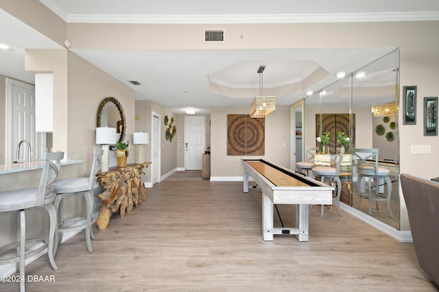 playroom with light hardwood / wood-style flooring, crown molding, and a tray ceiling