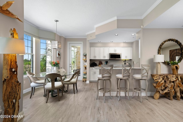 kitchen with crown molding, light wood-type flooring, a breakfast bar, white cabinets, and kitchen peninsula