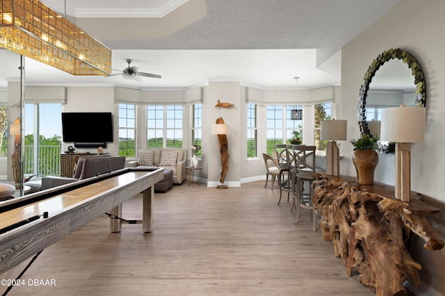 rec room featuring ornamental molding, a textured ceiling, ceiling fan, and light hardwood / wood-style flooring