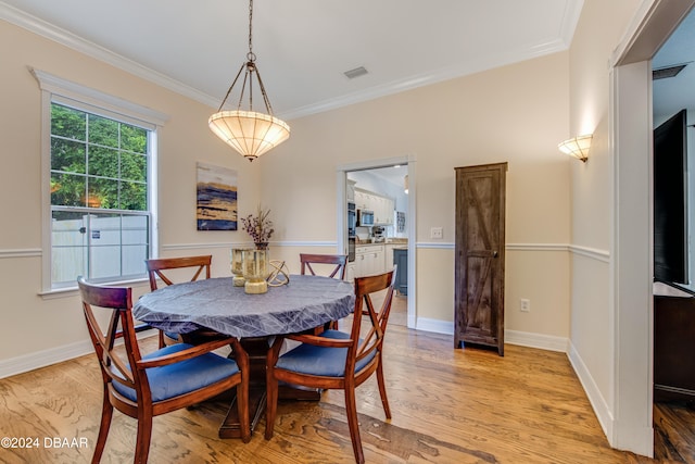 dining area with light wood-type flooring and crown molding