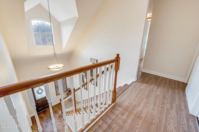 staircase with hardwood / wood-style floors and vaulted ceiling