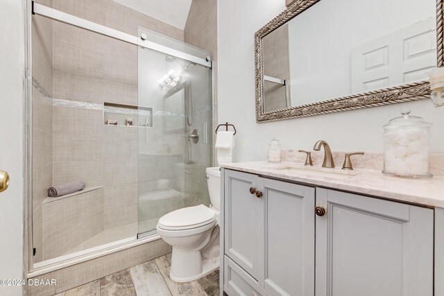 bathroom featuring hardwood / wood-style floors, a shower with shower door, vanity, and toilet