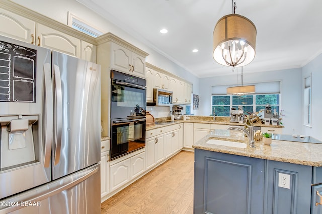 kitchen with black appliances, decorative light fixtures, light stone countertops, sink, and light hardwood / wood-style flooring