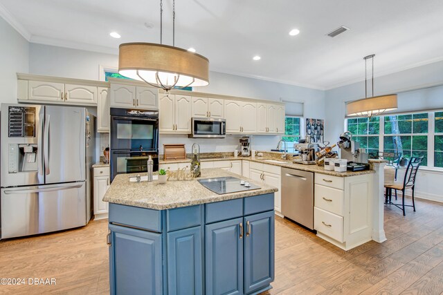 kitchen with hanging light fixtures, light hardwood / wood-style floors, black appliances, and an island with sink