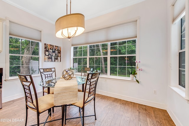 dining area with light wood-type flooring, crown molding, and plenty of natural light