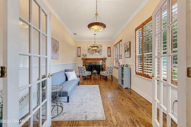 sitting room with hardwood / wood-style flooring, a high end fireplace, plenty of natural light, and ornamental molding