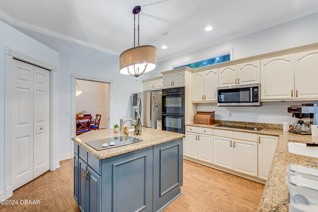 kitchen with black appliances, an island with sink, light hardwood / wood-style flooring, crown molding, and pendant lighting