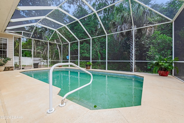 view of pool with glass enclosure and a patio