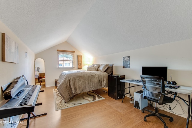 bedroom featuring light hardwood / wood-style flooring, lofted ceiling, and a textured ceiling