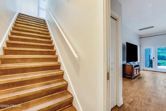 stairs with french doors and hardwood / wood-style floors