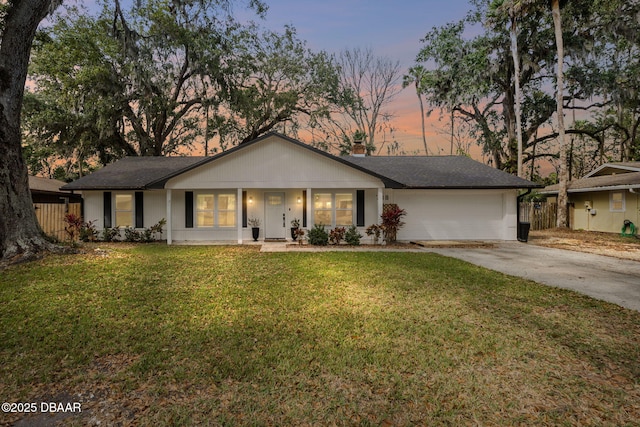 ranch-style home featuring a chimney, driveway, an attached garage, and a front yard