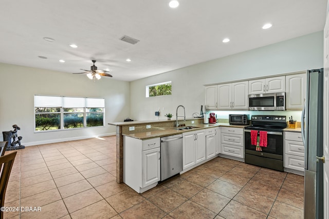 kitchen with light tile patterned flooring, appliances with stainless steel finishes, sink, white cabinets, and kitchen peninsula