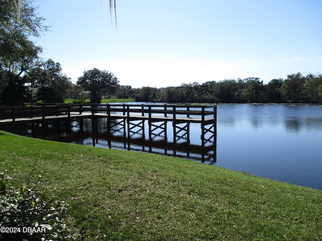 view of dock featuring a lawn and a water view