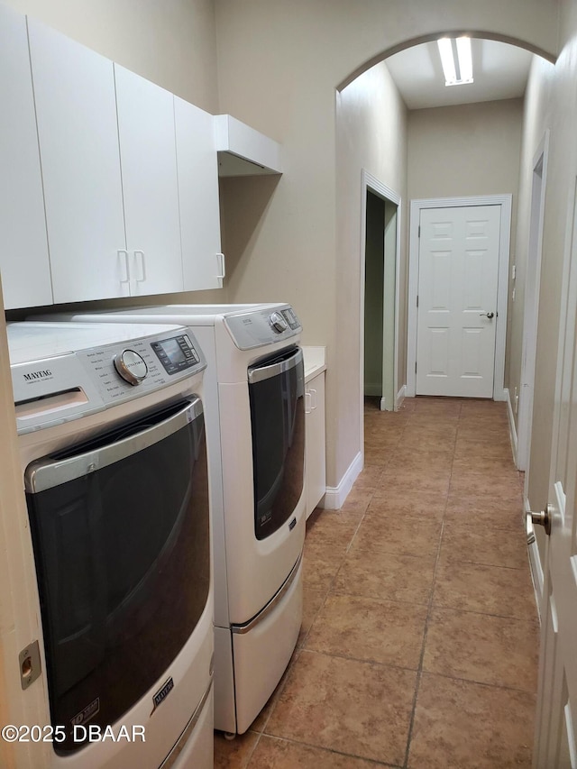 7 Old Mcduffie Cir, Ormond Beach, FL 32174 - laundry room with arched walkways, washer and clothes dryer, cabinet space, baseboards, and light tile patterned floors