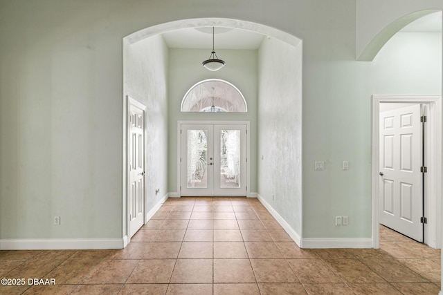 7 Old Mcduffie Cir, Ormond Beach, FL 32174 - foyer with french doors, a high ceiling, baseboards, light tile patterned flooring, and arched walkways