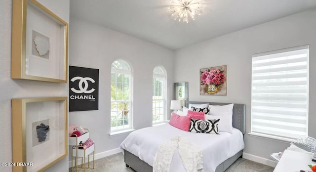 bedroom featuring carpet floors, multiple windows, and a notable chandelier