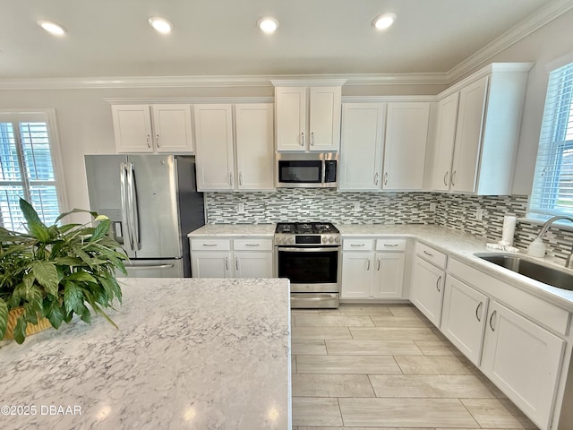 24 Shear Water Trl, Ormond Beach, FL 32174 - kitchen featuring stainless steel appliances, a sink, plenty of natural light, white cabinets, and crown molding
