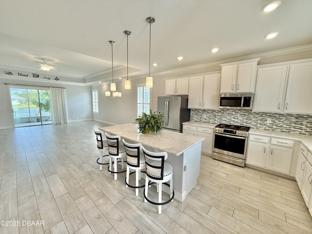 24 Shear Water Trl, Ormond Beach, FL 32174 - kitchen with stainless steel appliances, crown molding, backsplash, a kitchen island, and a breakfast bar