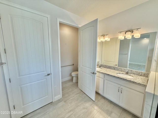 24 Shear Water Trl, Ormond Beach, FL 32174 - full bathroom featuring toilet, double vanity, wood finished floors, and baseboards