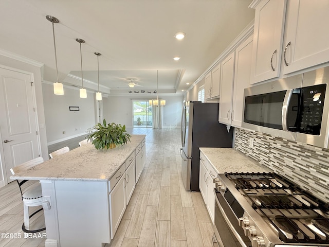 24 Shear Water Trl, Ormond Beach, FL 32174 - kitchen featuring appliances with stainless steel finishes, a center island, light wood finished floors, a kitchen bar, and crown molding