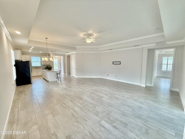 24 Shear Water Trl, Ormond Beach, FL 32174 - unfurnished living room featuring a raised ceiling, ceiling fan, ornamental molding, baseboards, and light wood-type flooring
