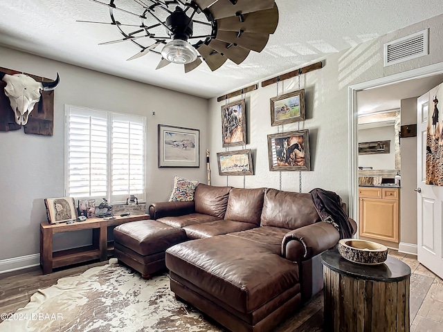 living room with hardwood / wood-style floors, a textured ceiling, and ceiling fan