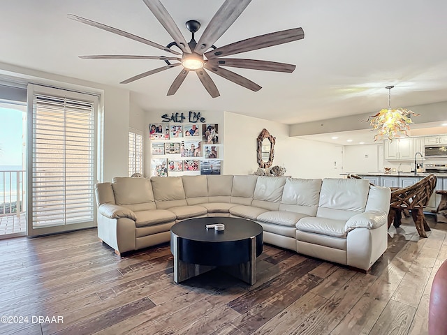 living room with hardwood / wood-style floors, ceiling fan with notable chandelier, and sink