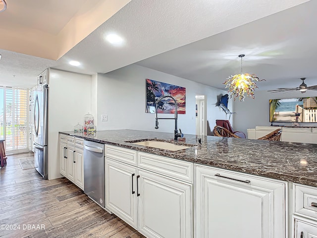 kitchen with appliances with stainless steel finishes, dark hardwood / wood-style flooring, a textured ceiling, pendant lighting, and white cabinetry