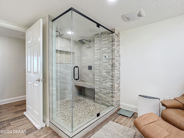 bathroom with a shower with door, wood-type flooring, and a textured ceiling