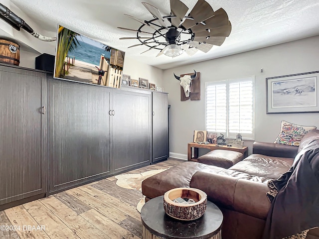 living room with ceiling fan, light hardwood / wood-style flooring, and a textured ceiling