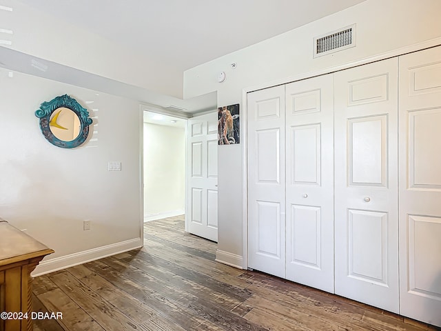 unfurnished bedroom featuring a closet and dark wood-type flooring