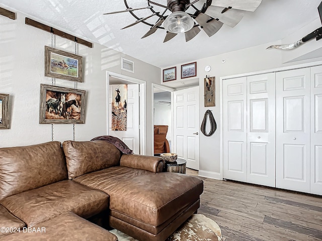 living room with hardwood / wood-style flooring, ceiling fan, and a textured ceiling