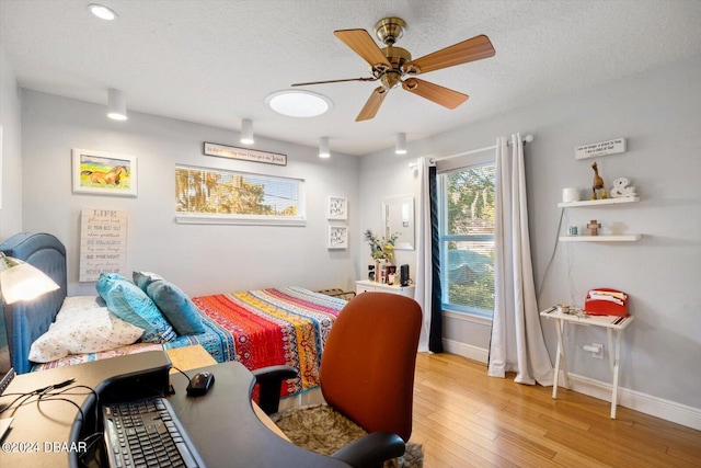 bedroom featuring hardwood / wood-style floors, ceiling fan, and a textured ceiling