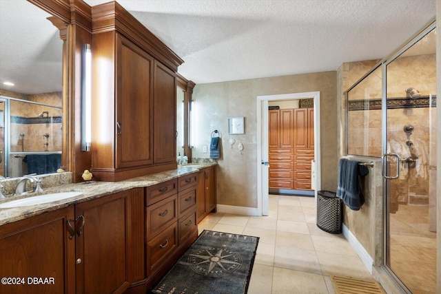 bathroom with vanity, a shower with shower door, a textured ceiling, and tile patterned floors